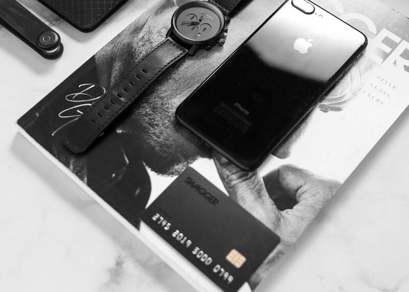 Black and white flat lay showcasing a stylish desk with phone, watch, and accessories.